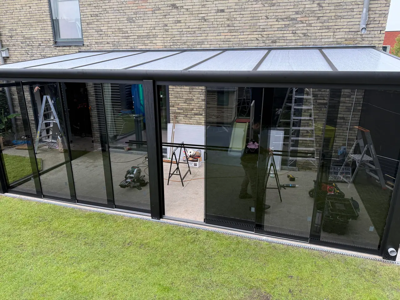 Ein Monteur von SAVA Glass montiert eine Glasschiebewand beim Kunden